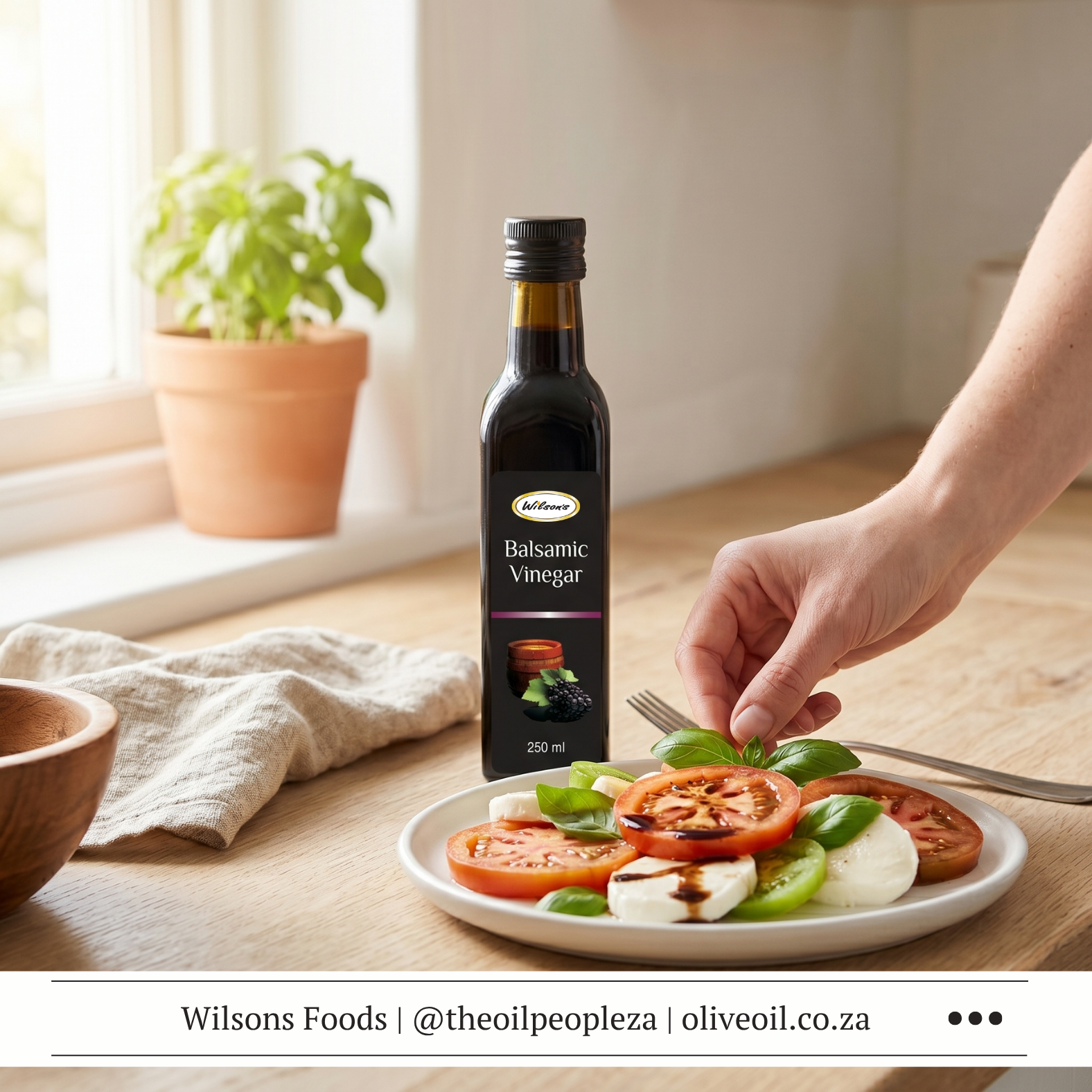 Articles 2 Wilson's Foods Balsamic Vinegar bottle on a wooden surface with fresh tomatoes, basil and mozzarella alongside