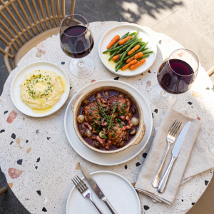 Coq au vin chicken braised in red wine sauce with bacon and mushrooms in a pot